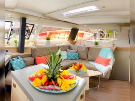 A beautifully arranged interior of a boat featuring a cozy seating area and a vibrant fruit platter, perfect for enjoying meals while cruising.
