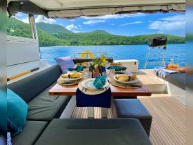 An elegantly set dining area on a boat, featuring beautifully arranged plates and glasses, perfect for enjoying meals while surrounded by stunning views of nature.