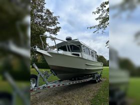 A sleek boat is showcased on its trailer, highlighting its design and features in a serene outdoor setting.