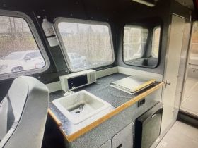 Interior view of a boat's helm area featuring a sink, microwave, and workspace — ideal for comfort and functionality on the water.