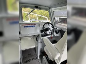 The interior of a North River boat showcasing the helm and seating area, designed for comfort and functionality while navigating the waters.