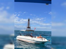 A group enjoys a day on the water with a boat anchored near a lighthouse, perfect for swimming and snorkeling adventures.
