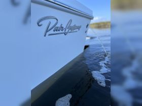 Close-up of the hull of a boat featuring the name 'Pairing' with water splashing around, showcasing the sleek design and craftsmanship of the vessel.