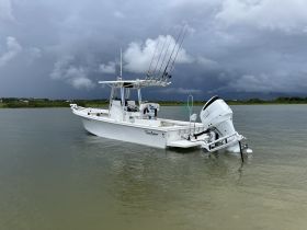 A sleek speedboat is anchored in calm waters under a dramatic sky, showcasing its design and fishing gear — perfect for adventure seekers.