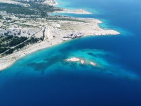 A stunning aerial view of a rugged coastline with turquoise waters, showcasing the natural beauty of the landscape — perfect for exploring hidden beaches and island adventures.