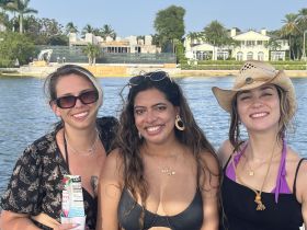 Three friends enjoy a sunny day on the water, capturing a moment of joy and celebration against a beautiful waterfront backdrop.