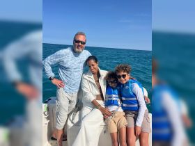 A joyful family poses on a boat, enjoying a sunny day on the ocean, all wearing life jackets for safety — perfect for memorable family adventures on the water.