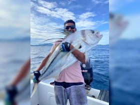 An enthusiastic angler proudly displays his impressive catch while fishing in the open ocean — a perfect moment for fishing enthusiasts.