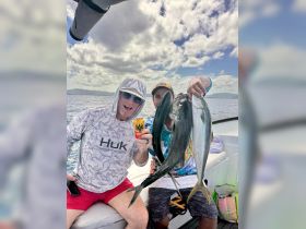 Two anglers proudly display their catch of the day while enjoying a fishing trip on the water, showcasing the thrill of deep-sea fishing.