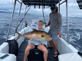 A joyful moment on a fishing trip as a woman proudly holds her catch aboard a boat, showcasing the thrill of deep-sea fishing adventures.