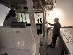 A serene moment inside the helm of a World Cat boat, featuring two individuals enjoying the sunset view while navigating the waters.