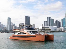 A stylish yacht glides through the waters with a stunning city skyline in the background, showcasing a perfect blend of luxury and urban scenery.