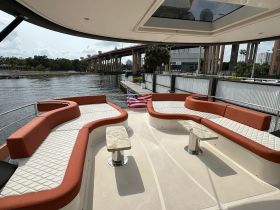 A spacious lounge area on a boat featuring comfortable seating and a stylish table, perfect for relaxing while enjoying views of the water.