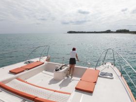 A woman enjoys the serene ocean view from the deck of a boat, perfect for a relaxing day on the water.
