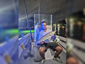 A proud angler displays his impressive catch during a night fishing adventure, showcasing the thrill of fishing under the stars.
