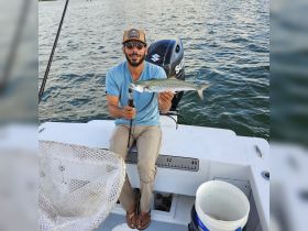 A proud angler holds up his catch aboard a boat, showcasing the thrill of fishing on the water. Perfect for fishing enthusiasts and adventure seekers.