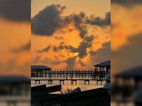 A stunning sunset view over a tranquil marina, showcasing the silhouettes of docks and boats against a vibrant sky — perfect for capturing the beauty of waterfront life.