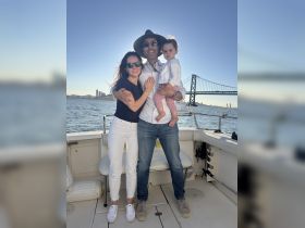 A joyful family poses together on a boat with a stunning waterfront view, capturing a memorable moment on the water.