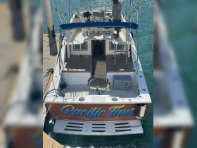 The back view of the 'Pacific Time' yacht docked, showcasing its spacious deck and helm area, ideal for fishing or leisure outings.