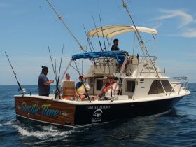 A group of friends enjoys a fishing trip aboard the 'Pacific Time' boat, showcasing camaraderie and adventure on the open water.