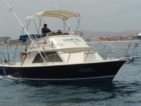 A fishing boat named 'Pacific Time' is underway, showcasing its sleek design against a coastal backdrop — perfect for sport fishing adventures.