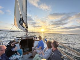 A group of friends enjoys a stunning sunset while sailing, creating a perfect backdrop for memorable moments on the water.