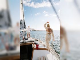 A couple enjoys a beautiful day sailing on the ocean, capturing a moment of joy and connection aboard their yacht.