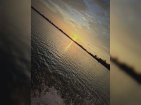 A stunning sunset reflects on the water, captured from a boat, showcasing the serene beauty of evening cruises.