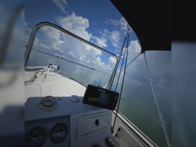 A view of the helm area on a boat, showcasing the console and navigation equipment against a backdrop of calm waters and a beautiful sky.