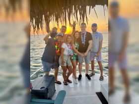 A lively group of friends celebrates at sunset aboard a boat, capturing the perfect moment for unforgettable memories on the water.