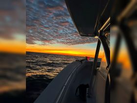 A stunning sunset view from the side of a boat, showcasing vibrant colors reflecting on the water — perfect for serene evening cruises.