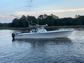 A fisherman enjoys a serene moment aboard a fishing boat, surrounded by tranquil waters and lush greenery — perfect for a day of fishing adventures.