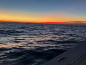 A blurred image capturing a sunset over the ocean, creating an abstract view of the water and sky.