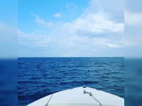A serene view from the front of a boat, showcasing the vast ocean and a clear blue sky — perfect for a day of fishing or cruising.