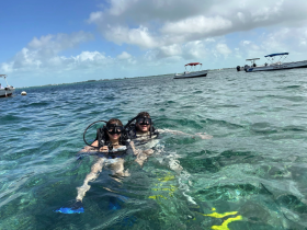 A couple enjoys snorkeling in clear waters, surrounded by boats, capturing the essence of adventure and exploration in a tropical paradise.