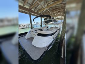 A sleek boat docked under a covered area, showcasing its elegant design and spacious deck, perfect for leisurely outings on the water.
