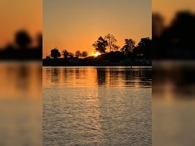 A stunning sunset casts a warm glow over the water, creating a picturesque reflection — perfect for capturing serene moments on the water.