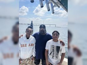 A joyful family poses together on a boat, enjoying a day on the water with a scenic backdrop — perfect for memorable outings and celebrations.