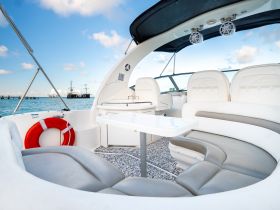 A spacious and stylish interior view of a boat's seating area, featuring comfortable cushions and a table, perfect for relaxing on the water.