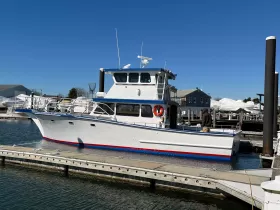 A well-maintained boat docked at the marina, showcasing its sleek design and vibrant colors against a clear blue sky.