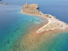 A stunning aerial view of a secluded island with turquoise waters and rocky coastline, perfect for exploring and enjoying nature's beauty.