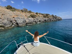 A woman enjoys the stunning coastal scenery while relaxing on the bow of a boat, capturing the essence of a perfect day on the water.