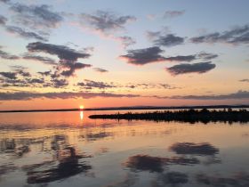 A stunning sunset casts vibrant colors over calm waters, creating a picturesque scene perfect for evening boat trips or romantic getaways.
