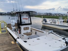 A well-equipped center console boat docked at a serene waterfront, showcasing its sleek design and fishing gear — perfect for a day out on the water.