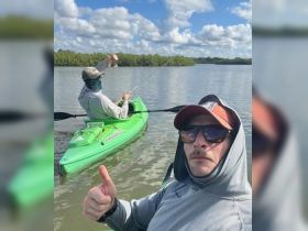 Two friends enjoy a day of kayaking and fishing in calm waters, showcasing the perfect outdoor adventure for nature lovers.