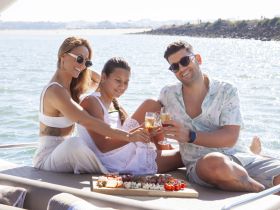 A joyful group toasts with cocktails aboard a yacht, enjoying a delicious spread of food — perfect for celebrations on the water.