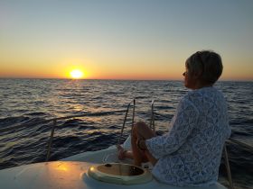 A serene moment as a woman enjoys the sunset from the deck of a boat, capturing the essence of relaxation on the water.