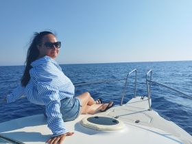 A woman relaxes on the bow of a boat, enjoying the serene ocean view — perfect for a day of leisure on the water.