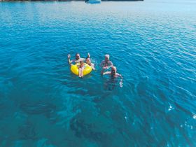 A joyful family enjoys a fun day in the water, with smiles and waves while floating on a yellow inflatable. Perfect for capturing memorable moments during summer adventures.