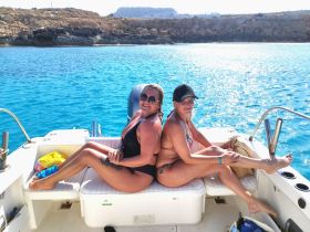Two friends enjoy a sunny day on a boat, soaking up the sun and the beautiful turquoise waters — a perfect setting for relaxation and fun on the water.